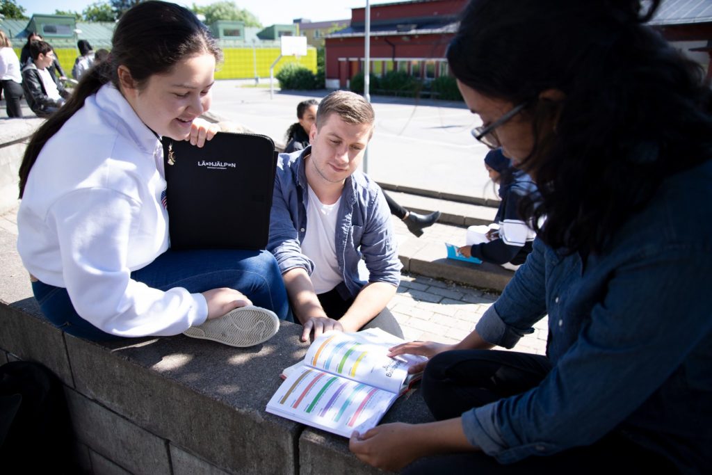 Personer sitter på skolgård och pluggar