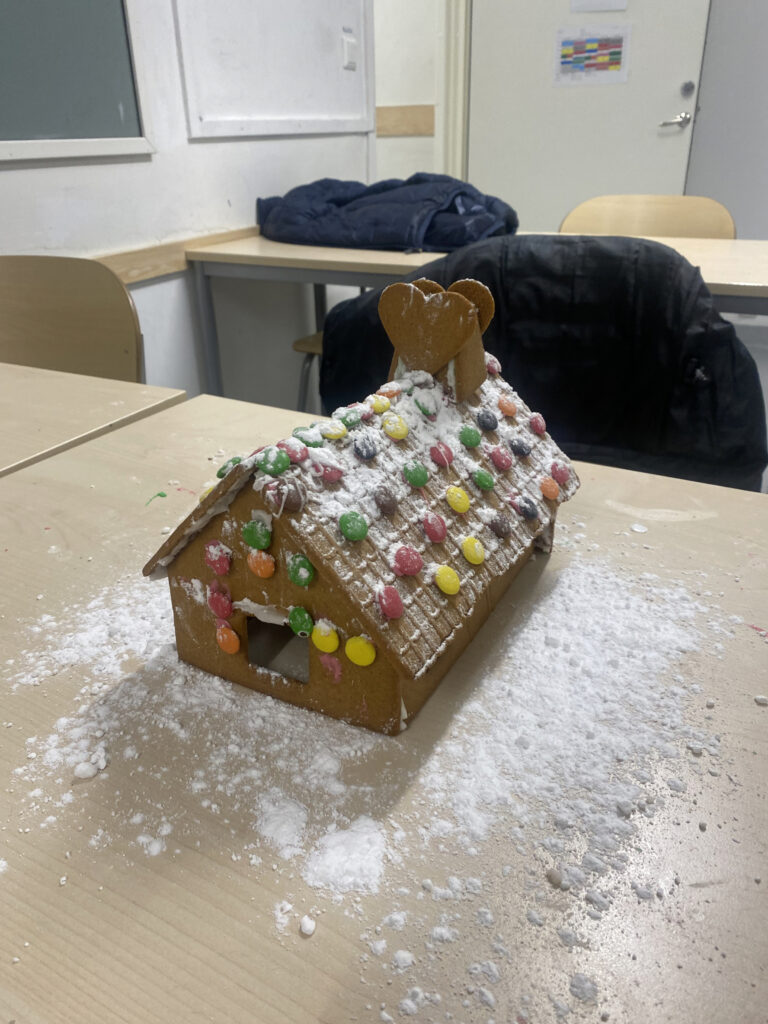 14. Gottsundaskolans MO1-grupp (Uppsala). Bilden föreställer ett pepparkakshus med ett tak klätt i vitt puder, taket är även dekorerat med non-stop choklad i olika färger samt pepparkakshjärtan. 

Kantväggen på huset är beklädd med non-stopchoklad.

Pepparkakshuset står på ett bord med vitt puder på.